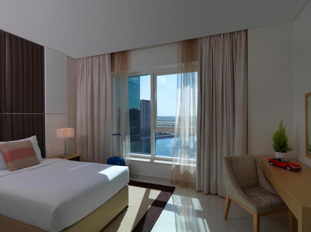 a bedroom with a bed and a desk and a window at DAMAC Maison Canal Views in Dubai