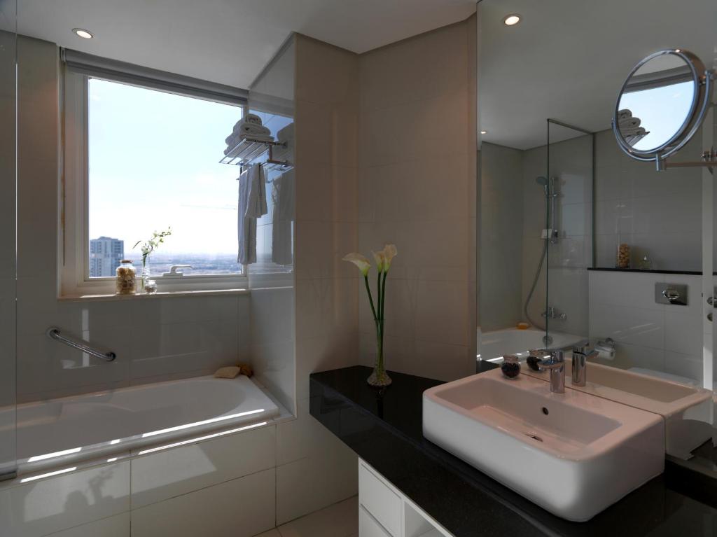 a bathroom with a sink and a tub and a mirror at DAMAC Maison Canal Views in Dubai