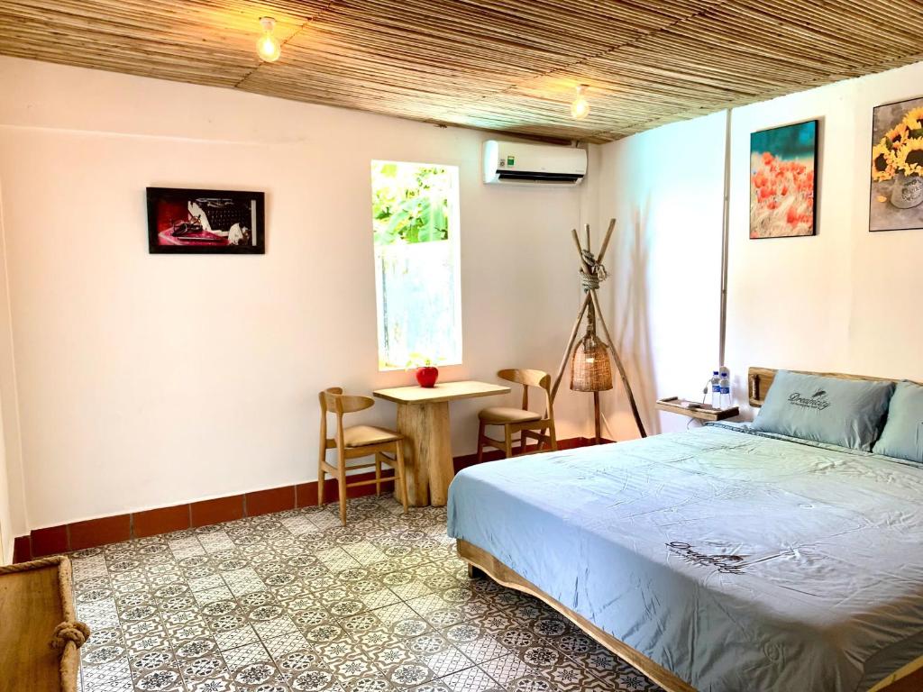 富国Ong Lang Cozy House with pool - 500m to the beach的一间卧室，里面有一张床、一张桌子和一扇窗户