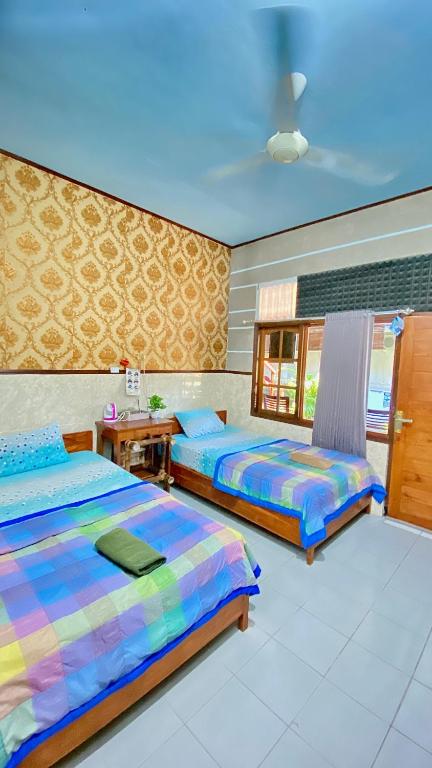 a bedroom with two beds and a table in it at Sawitri Homestay in Padangbai