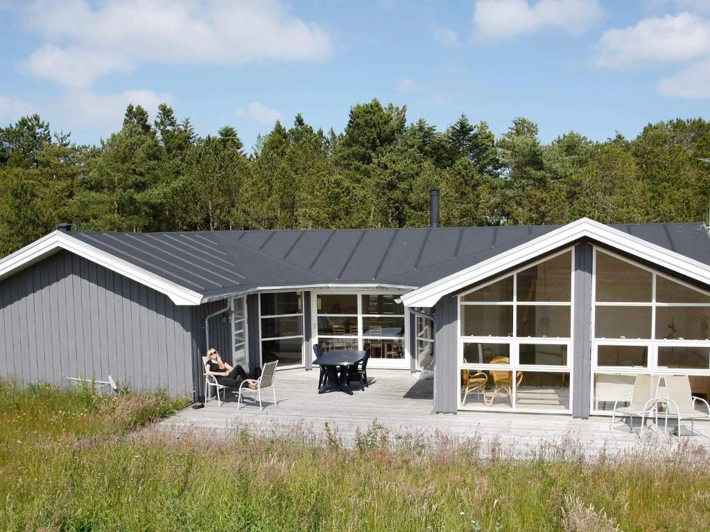 a woman sitting on a porch of a house at Luxury Retreat in Bratten - By Traum Ferienwohnungen in Jerup