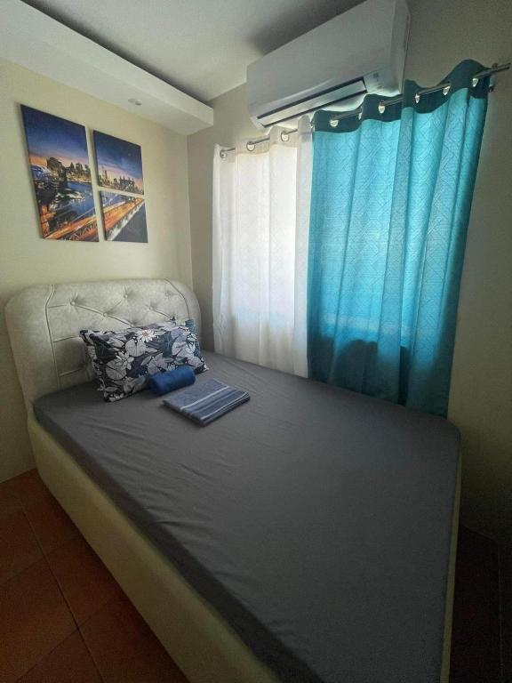 a bed in a room with a blue curtain at San Remo Oasis Cebu City U2331 in Cebu City
