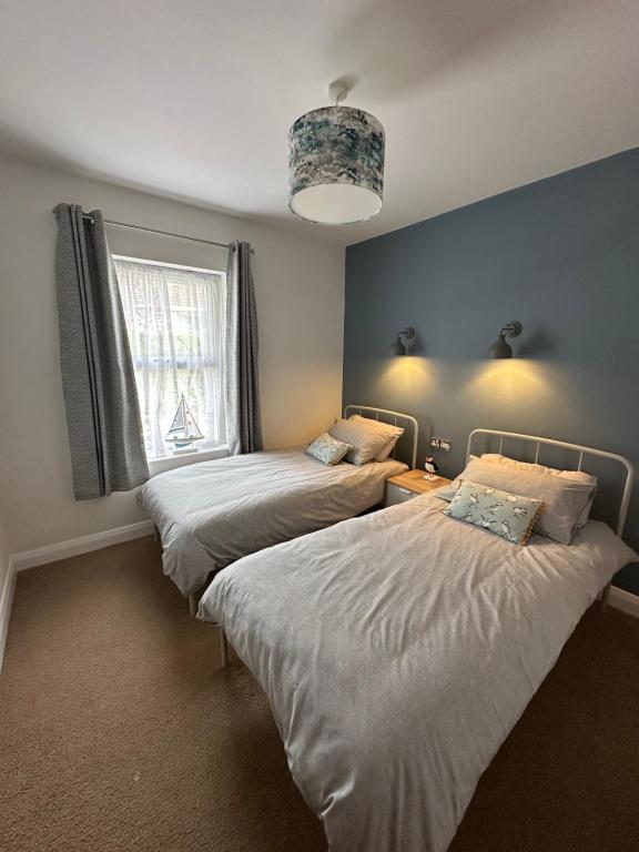 - une chambre avec deux lits, une fenêtre et un lustre dans l'établissement 27 By The Sea, à Ballycastle