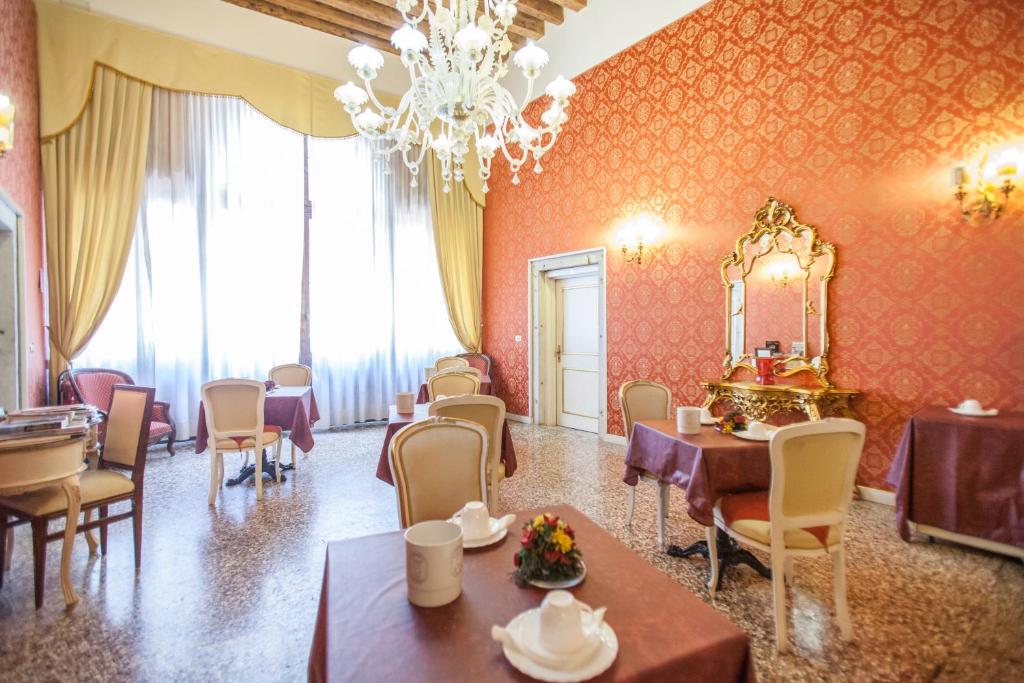 uma sala de jantar com mesas e cadeiras e um lustre em Locanda Barbarigo em Veneza