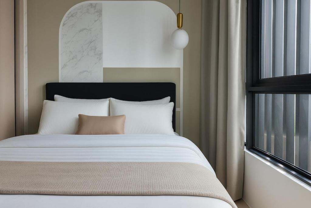 a bed with white pillows and a window at The Family Den Upton By Elica in Kuching