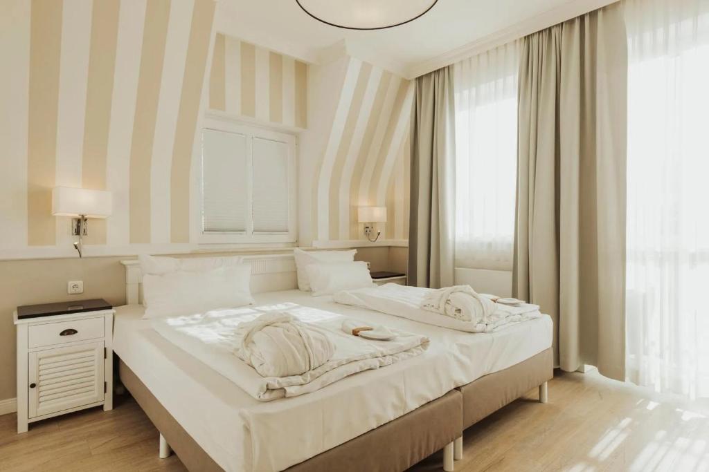 ein großes weißes Bett in einem Zimmer mit Fenster in der Unterkunft Villa Strandperle IV Jahreszeiten Kühlungsborn in Kühlungsborn