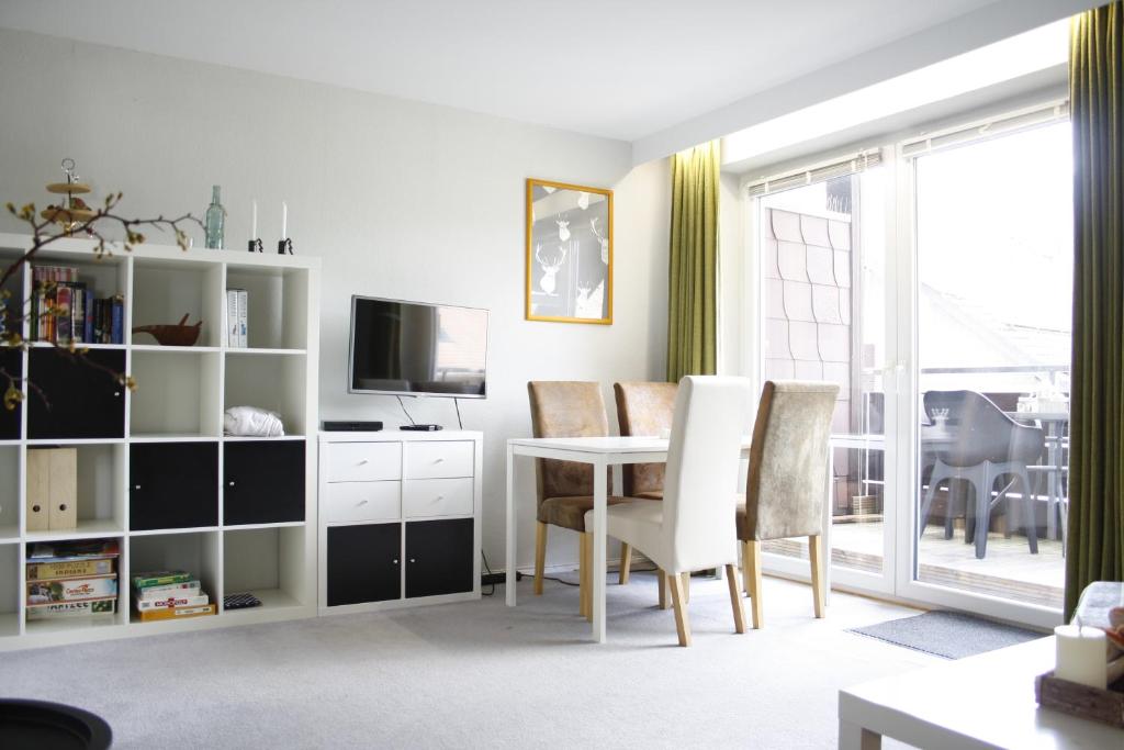 a living room with a table and chairs and a television at Harzlicht Braunlage - mit Balkon und Weitblick in Braunlage