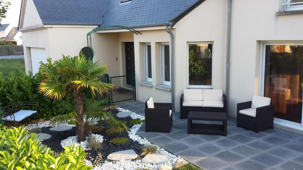 une terrasse avec 2 chaises et un palmier dans l'établissement Villa moderne à 200m de la mer avec jardin clos, à Saint-Vaast-la-Hougue