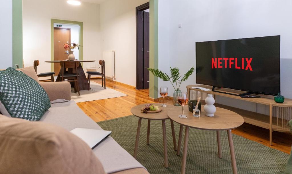 a living room with a tv and two tables with wine glasses at Central Thessaloniki Boutique in Thessaloniki