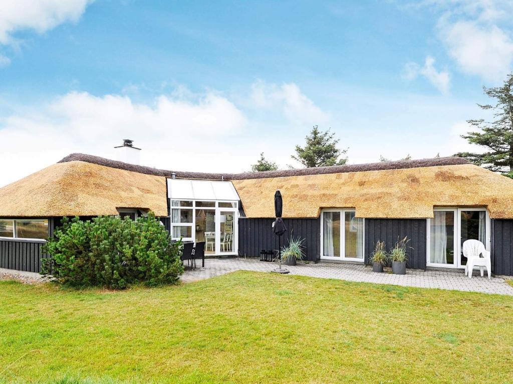 a thatch roofed house with a patio and a yard at Cozy Beach House in Vejers - By Traum Ferienwohnungen in Vejers Strand