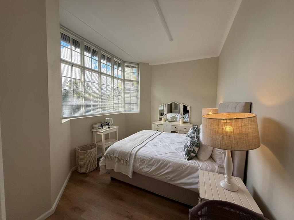 a bedroom with a bed and a table with a lamp at Railway Cottage at Rawdons Country Estate in Nottingham Road
