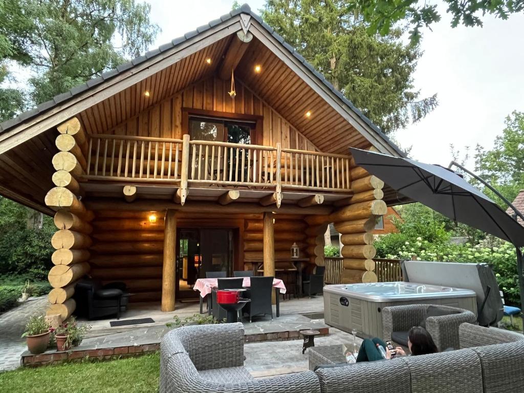 a log cabin with a deck and a pool at the loghouse in Aalter