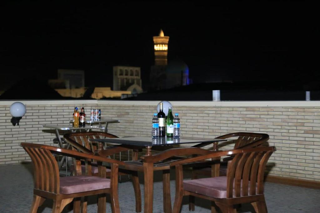 a table with four chairs and bottles of wine at SARROJ Boutique in Bukhara