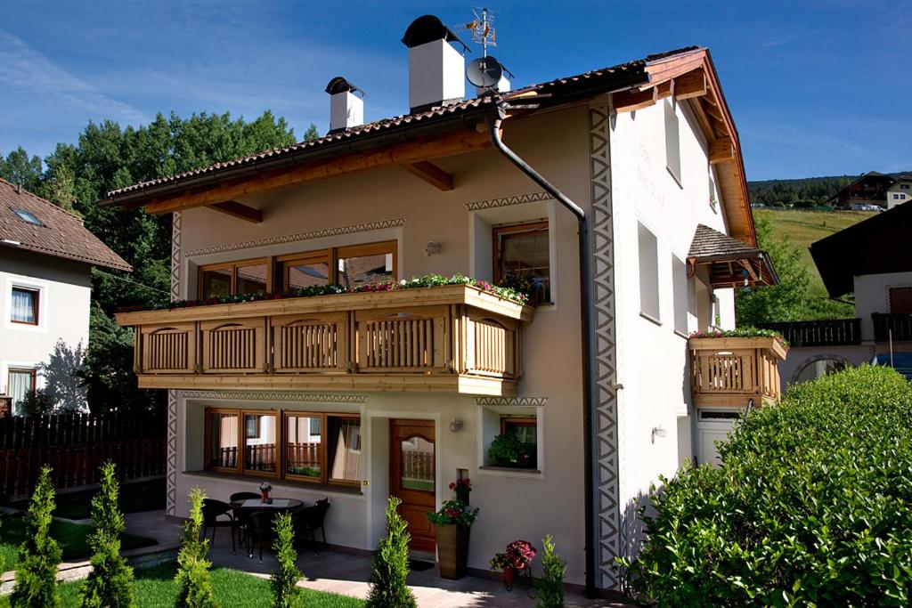 Cette grande maison blanche dispose d'un balcon et d'une table. dans l'établissement Cesa Sule de Sot, à Ortisei