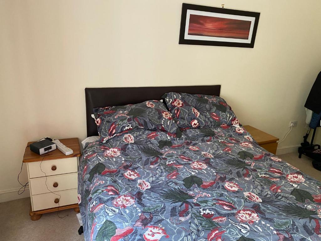 a bed with a floral comforter and a night stand at Woodstock in York