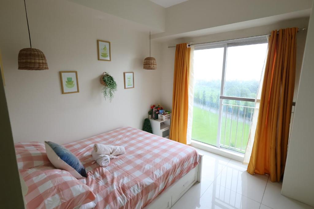 a bedroom with a bed and a large window at Great Escape 5th FLR GARDEN VIEW in Kaybagal