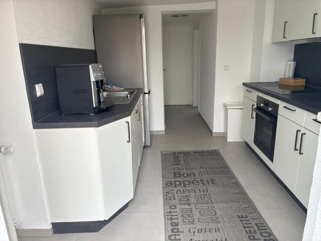 een keuken met witte kasten en een zwart aanrechtblad bij Unterm-Felsen in Bad Überkingen