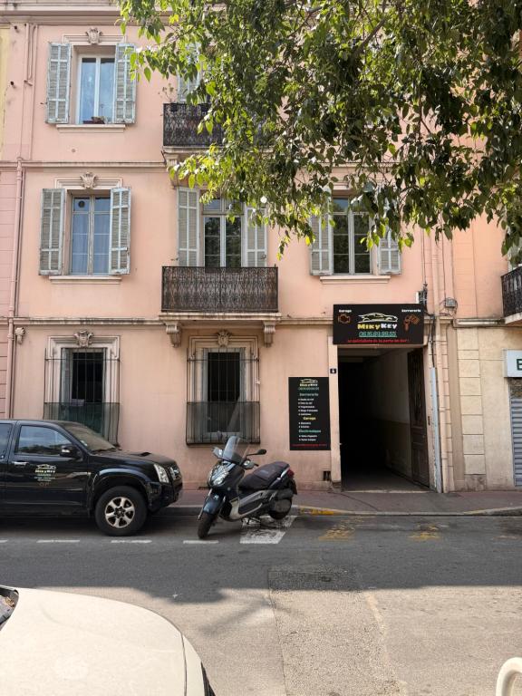 ein Motorrad, das vor einem rosa Gebäude parkt in der Unterkunft Le Rosy By ApiRent #Balcon #Wifi #Centre-ville in Cannes