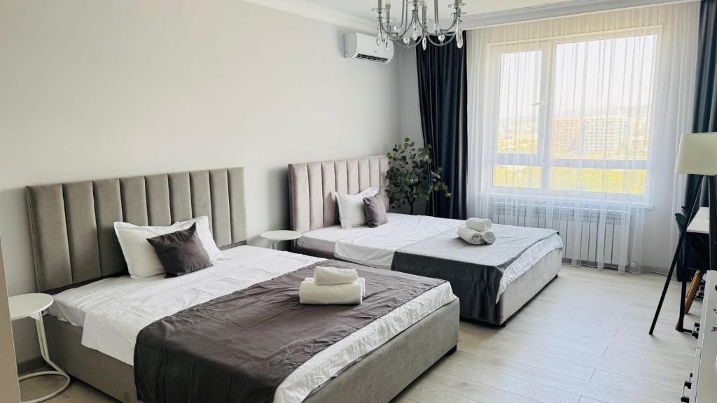 a bedroom with two beds and a chandelier at 1835 Rams City Mountain View Apartment in Almaty