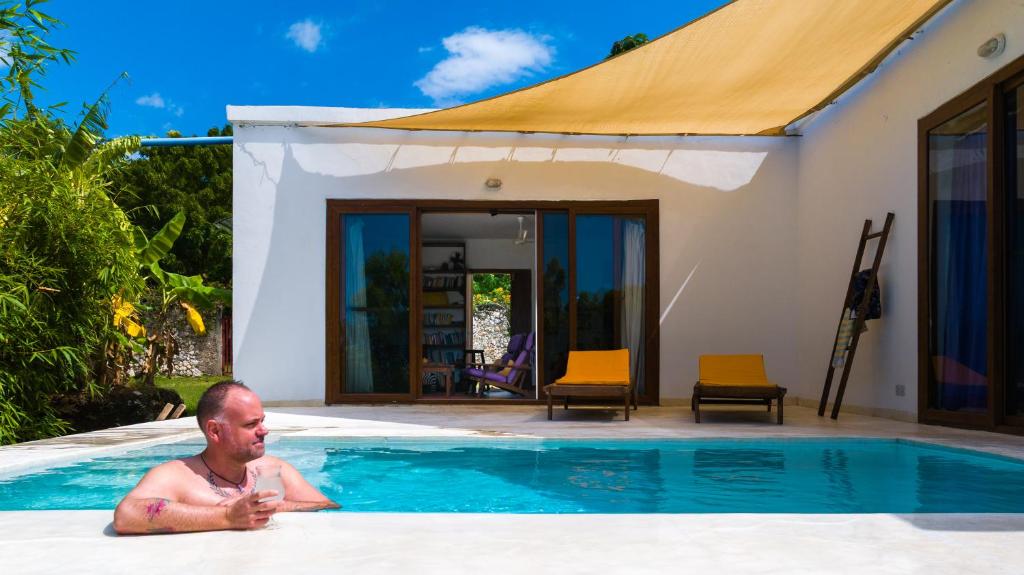 a man laying in a swimming pool next to a house at Matemwe House 1 in Matemwe