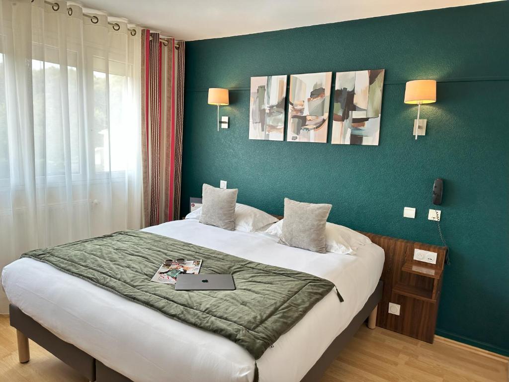 Hôtel Brun في Saint-Lattier: غرفة نوم بها سرير عليه جهاز كمبيوتر محمول