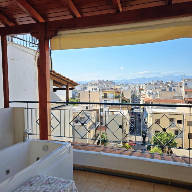 a balcony with a tub and a view of a city at Acropolis View Sky Suite with Jacuzzi near Metro in Athens
