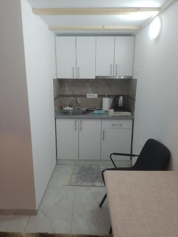 une cuisine vide avec des placards blancs et une table dans l'établissement Apartman Dragana, à Sremska Mitrovica