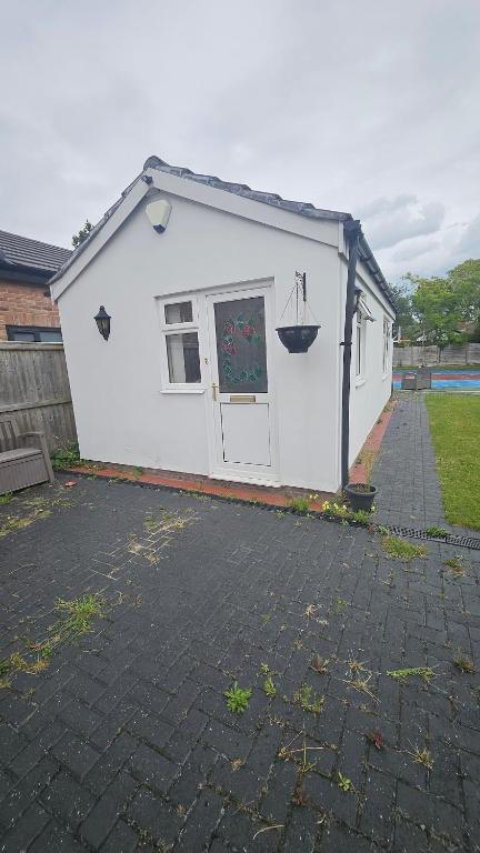 a white shed with a door and a window at Studio Flat - 5 mins from Manchester Airport in Baguley