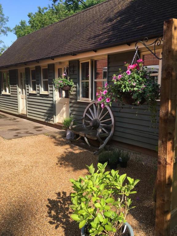 a house with a wheel and flowers in front of it at Mays Cottage Bed and Breakfast in Petersfield