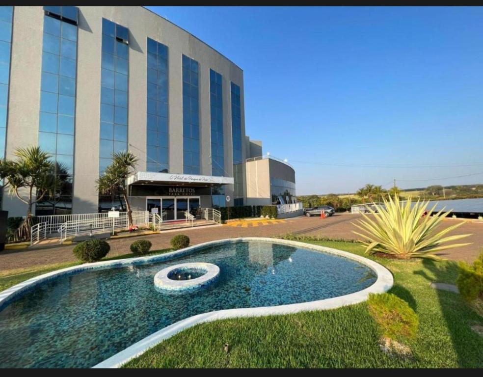 a building with a swimming pool in front of a building at Barretos Park Hotel-Apartamento João e Maria in Barretos
