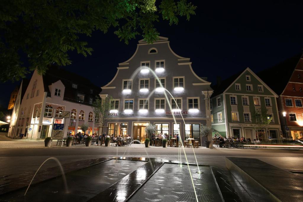 budynek z fontanną w środku ulicy w nocy w obiekcie Hotel am Schrannenplatz w mieście Memmingen