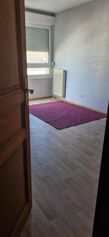 una habitación vacía con una puerta y una alfombra púrpura en A private room in a flat shared familly home, en Mulhouse