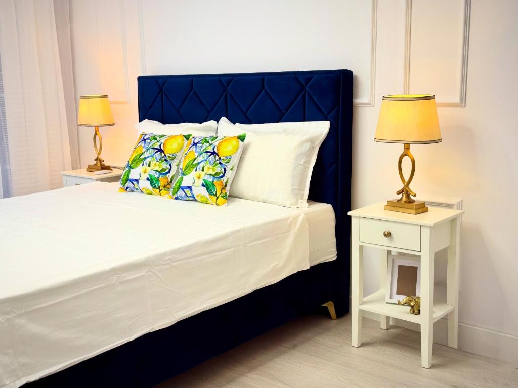 a bedroom with a bed with a blue headboard and two lamps at Boutique Apartment in Ploieşti