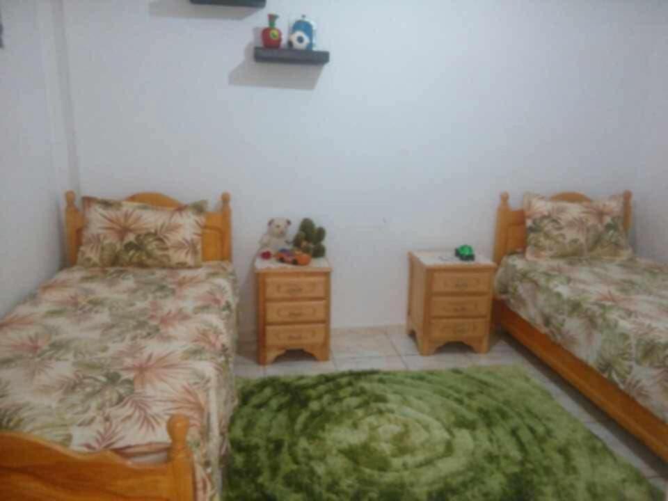 a bedroom with two beds and a green rug at vacation house 120 dt par nuitée kélibia in Kelibia