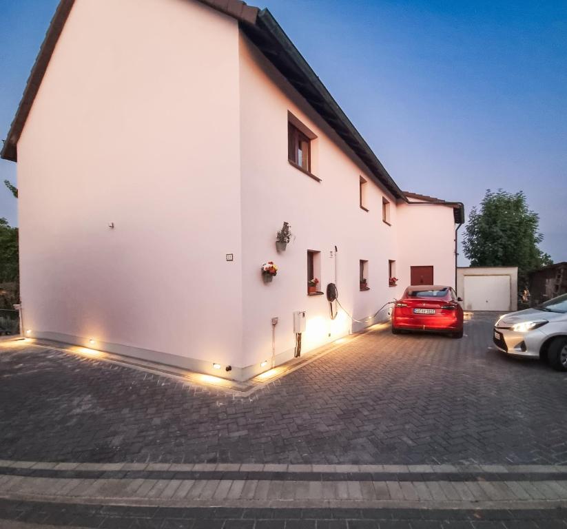 a white building with cars parked in a parking lot at Naturblick Apartment - Modernes 3-Zimmer mit Privatparkplatz in Neustadt bei Coburg