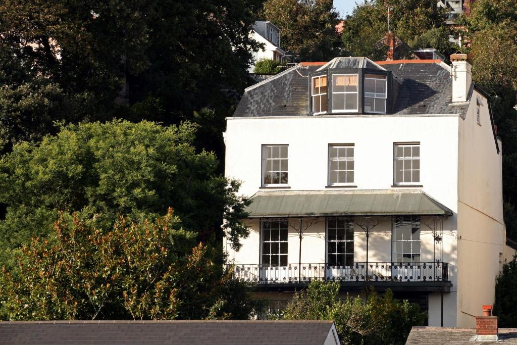 een wit huis met een balkon op een heuvel bij Lammas Park House in Dawlish