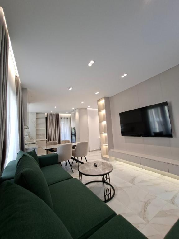 un soggiorno con un divano verde e una TV di Oneluxury a Tirana