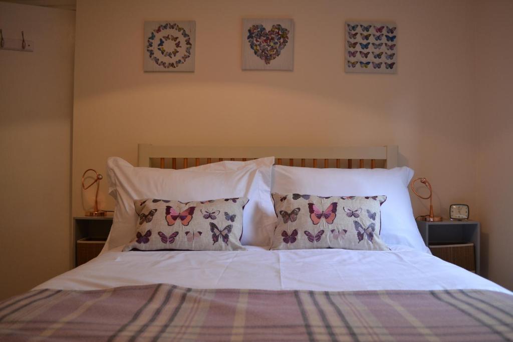Una cama con sábanas blancas y almohadas con mariposas. en Boat Green Apartment, en Edimburgo
