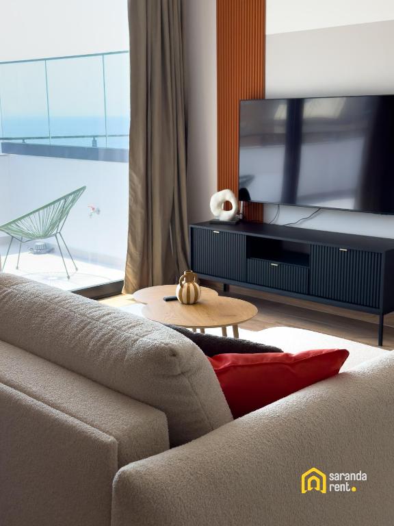 a living room with a couch and a flat screen tv at The Calaya - Aparthotel Saranda in Sarandë