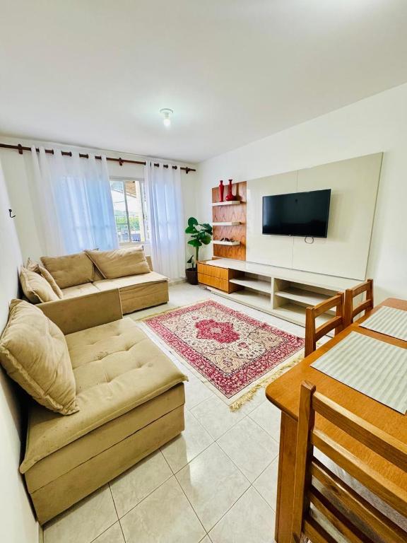 a living room with a couch and a flat screen tv at Apartamento coração de arraial in Arraial do Cabo