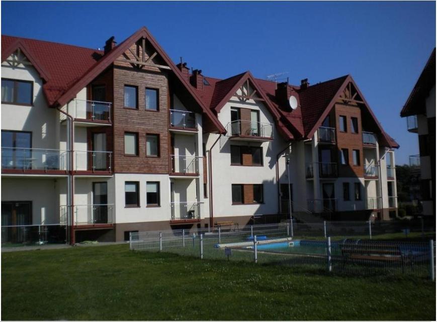 un grand immeuble d'appartements avec une pelouse devant lui dans l'établissement Apartament Anita, à Jastrzębia Góra