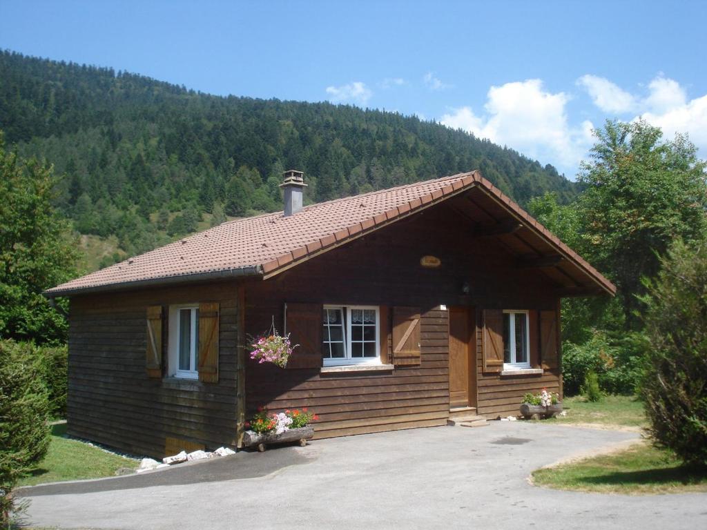 ein kleines Holzhaus mit einem Berg im Hintergrund in der Unterkunft Chalet Confortable à La Bresse, Proche Ski, Wifi, Animaux Acceptés - FR-1-589-130 in La Bresse