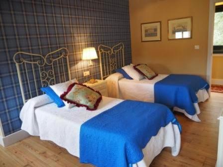 um quarto de hotel com duas camas com lençóis azuis em La Calleja em Arzúa