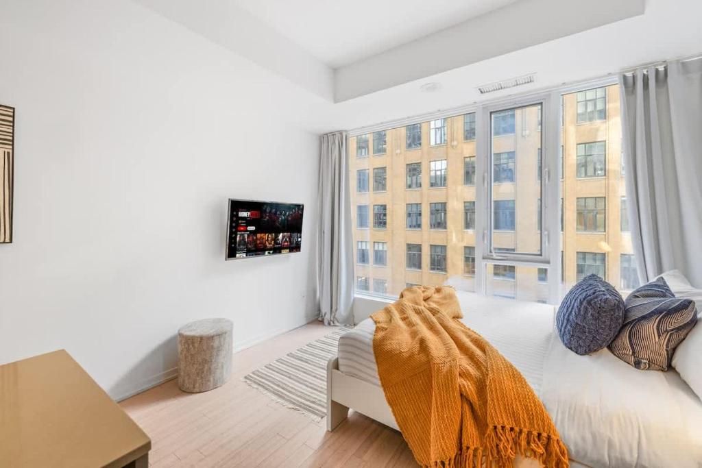 a white bedroom with a large window and a couch at Urban Oasis Central Studio Condo Perfect Getaway in Toronto