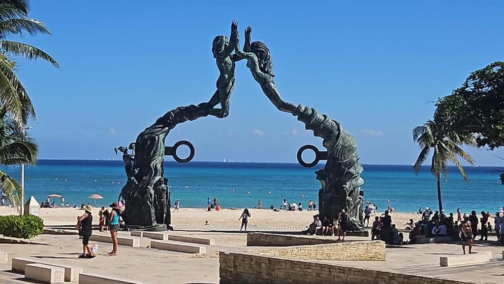 a statue on a beach with people on the beach at Enjoy yourself in Heaven! in Playa del Carmen