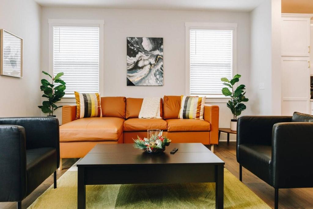 ein Wohnzimmer mit einem orangefarbenen Sofa und einem Couchtisch in der Unterkunft Birdsong Bungalow - Hot Tub, Game Room, Fire Pit in Charlotte