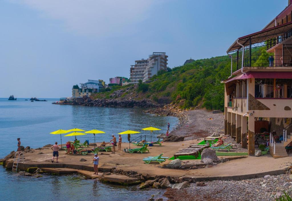 a beach with yellow umbrellas and people on it at Ai-Todor Hotel in Bondarenkovo