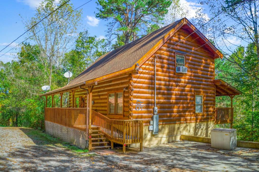 a log cabin in the woods with a porch at Firefly Dream - Smoky Escape Getaway with Theater, Firepit & Pool Table in Sevierville