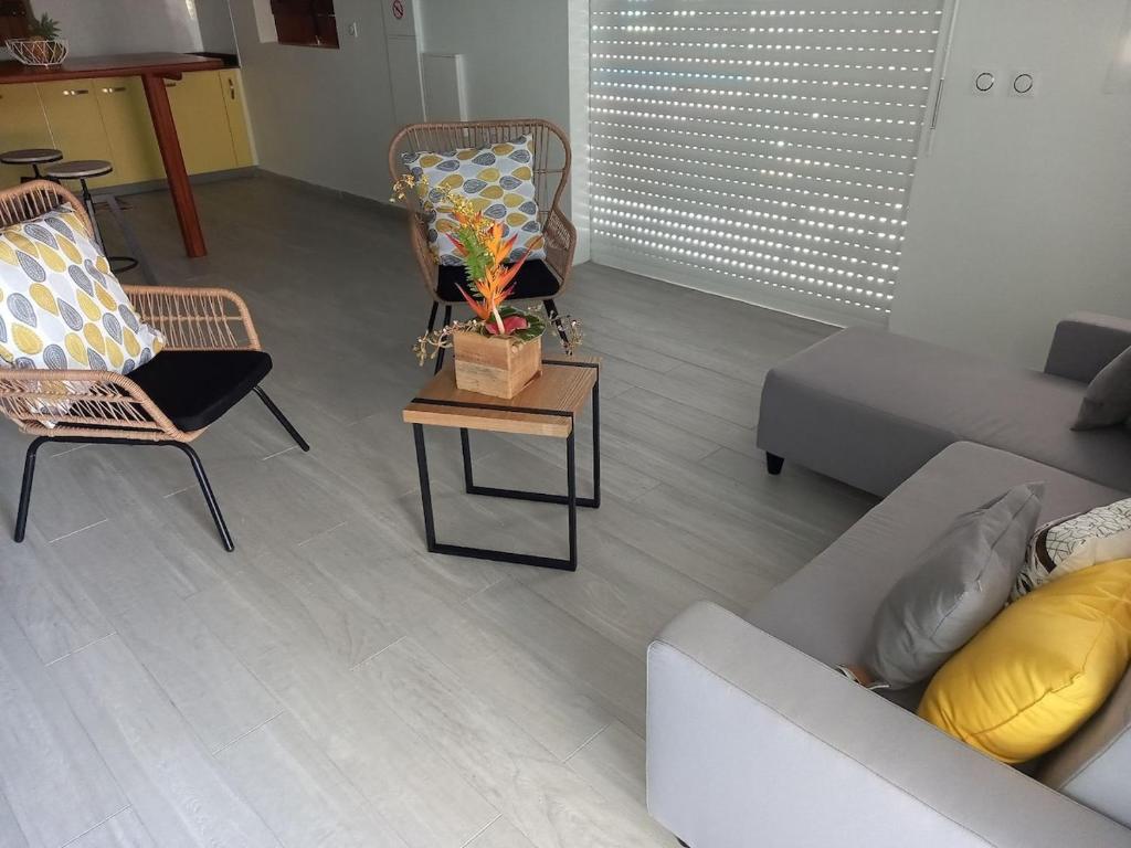 a living room with a couch and chairs and a table at L ombre du manguier in Grand-Bourg