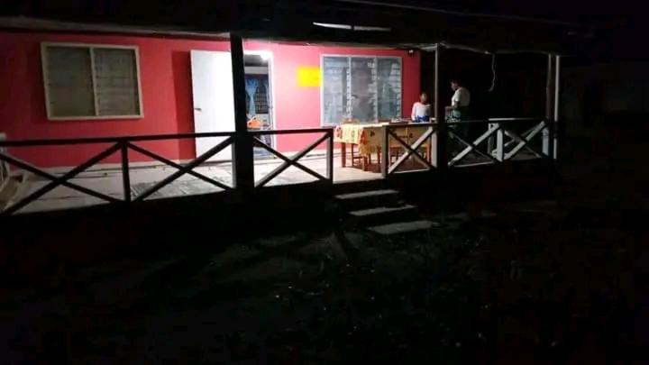 にあるNenas Homestayの夜にポーチに立っている人々のいる赤い家